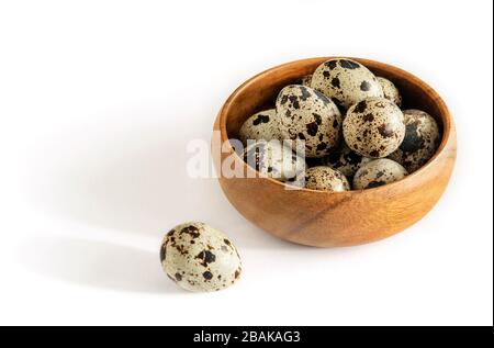 Wachtel hat Eier in einer Schüssel aus Naturholz auf dem weißen Hintergrund isoliert gesichtet. Natürliche gesunde Ernährung. Stockfoto