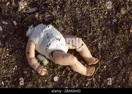 Plastikpuppe ohne Kopf mit Löchern aus Kugeln und Waffenpellets. Kriegsanmaßung Stockfoto