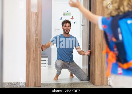 Kleiner Junge, der zu seinem Vater läuft und zu Hause auf ihn wartet Stockfoto