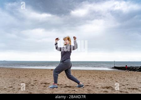 Portobello, Schottland, Großbritannien. März 2020. Am ersten Wochenende des Coronavirus Lockdown war die Öffentlichkeit draußen, die soziale Distanzierung entlang der Strandpromenade von Portobello ausübten und beibehalten. Abgebildet: Annabel Meikle aus Portobello arbeitet an ihrem speziellen, von ihrem persönlichen Trainer festgelegten, covid-19-Solo-Trainingsprogramm. Iain Masterton/Alamy Live News Stockfoto