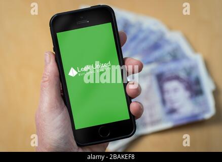 Eine Frau, die ein Mobiltelefon hält und Leek United Building Society zeigt (nur redaktionelle Verwendung) Stockfoto