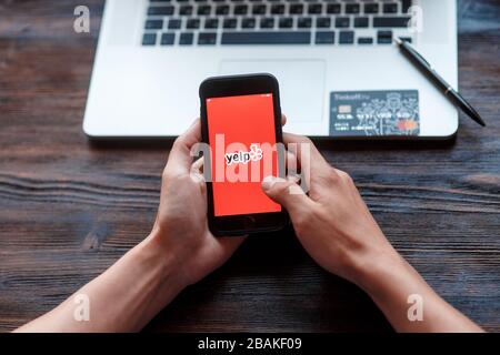 Frau hält Apple iPhone X mit yelp.com Website auf dem Bildschirm. Suchseite. Stockfoto