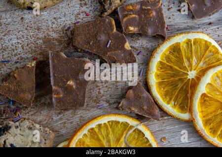 Getrocknete Orangen, Schokoladenscheiben, Schokoladengebäcke und Zimt auf einem Holztisch Stockfoto