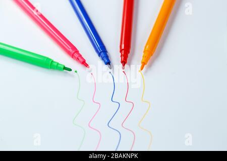 Viele mehrfarbige Markierungen zum Zeichnen mit Zeichnungen auf weißem Papier Stockfoto