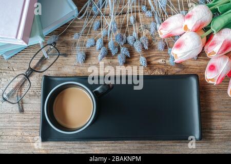 Kaffee in schwarzer Tasse mit Tablett und schöner Mockup-Dekoration auf Holztisch. Vogelperspektive, Mock-up-Konzept Stockfoto
