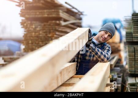 Junger männlicher Arbeiter im Holzlager Stockfoto