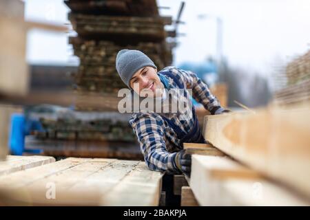 Junger männlicher Arbeiter im Holzlager Stockfoto