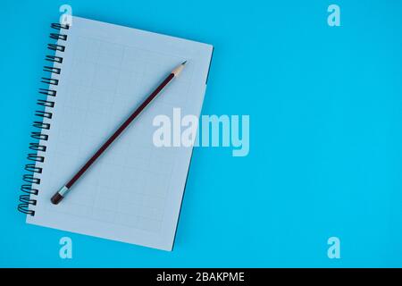 Violetter Bleistift auf einem weiß geöffneten Tagebuch vor einem hellblauen Papierhintergrund Stockfoto