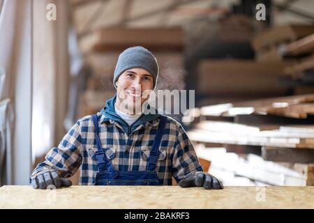 Junger männlicher Arbeiter im Holzlager Stockfoto