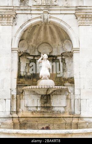 Alter Wasserbrunnen in einer weißen Steinmauer mit Statue und verzierter Schalenornamentik in Lamego, Portugal Stockfoto