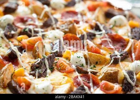 Nahaufnahme von Pizza mit Fleisch, Kartoffel, Zwiebel, Gemüsebelag Stockfoto