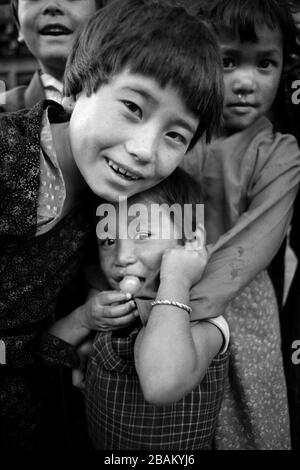 Kinder von Silberschmieden sind neugierig und schüchtern mit einem Ausländer, in der Nähe von Denshensholing, Bhutan, Stockfoto