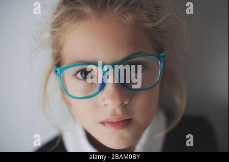 Schönes kleines trauriges Mädchen in blauer Brille Stockfoto