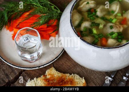 Suppe mit Knödel und Wodka auf einem Holztisch Stockfoto