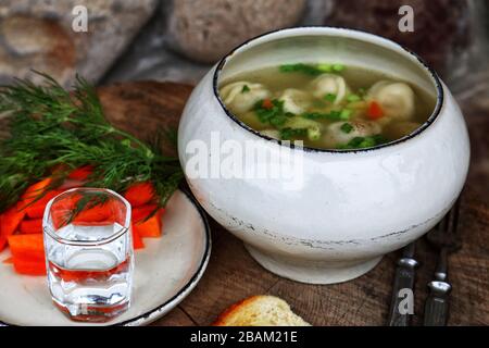 Suppe mit Knödel und Wodka auf einem Holztisch Stockfoto