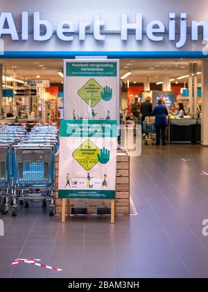 Coronavirus-Zeichen, die Regeln für Hygiene und soziale Distanzierung außerhalb eines Albert Heijn Supermarktes in Veenendaal, Niederlande, erklären Stockfoto