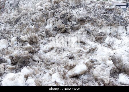 Viel Schnee und lockeres Eis verdunkelten sich durch Sättigung mit Schmelzwasser in den Strahlen der Frühlingssonne Stockfoto