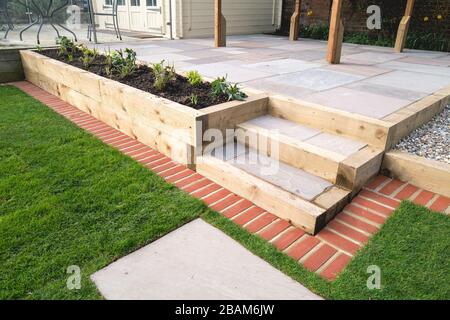 Eine neue, erhöhte Terrasse mit einem Holzgazebo vor einem erhabenen