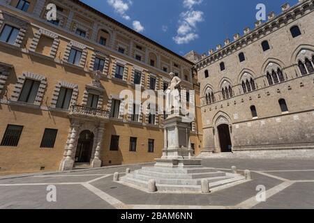 Die Statue von Sallustio Bandini auf der Piazza Salimbeni mit Rocca Salimbeni auf der rechten Seite und Palazzo Tantucci auf der linken Seite in Siena, Italien Stockfoto