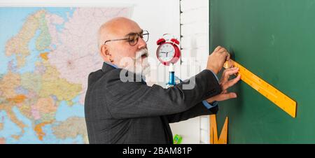 Lehrer des höheren Mannes verwenden Lineal beim Zeichnen. Tutor Mann in Brille zieht mit Lineal auf die Tafel. Zurück zur Schule. Welcher Winkel Sie sehen. Geometrische Formen. Moderne Ausbildung in der High School. Stockfoto