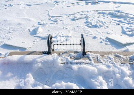 Eine Leiter, die nach einem Polar Vortex zu einem Schnee- und eisbedeckten Michigansee in Chicago führt Stockfoto