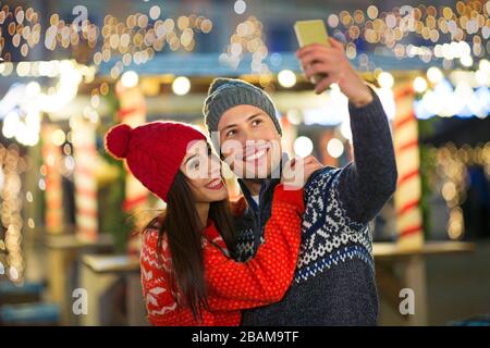 Junge Paare, Die Sich Zu Weihnachten Im Freien Vergnügen Stockfoto
