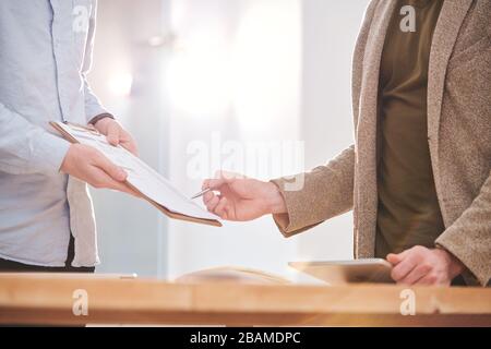 Nahaufnahme von Geschäftsleuten, die Kollegen Papiere zeigen, während sie mit ihm im Büro Finanzzahlen analysieren Stockfoto