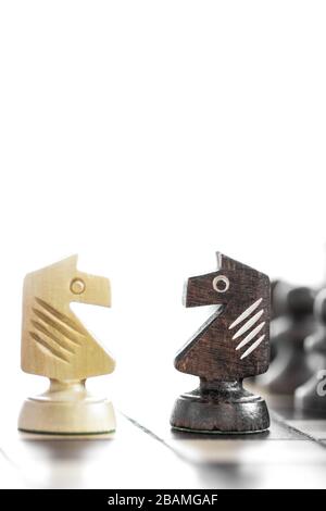 Schachfiguren aus Holz auf einem Schachbrett. Schwarz-weißes Schach auf Schachbrett, in weißem Hintergrund. Schachpferd an Bord. Stockfoto