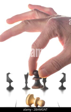 Schachkonzept mit Mann in Bewegung. Hand, die schwarze Schachfigur auf dem Schachbrett hält. Stockfoto