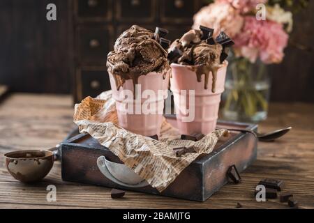 Schokoladenjoghurt schmeckt hausgemachte Eiskugeln in einer Tasse, Sommersonden auf rustikalem Hintergrund Stockfoto