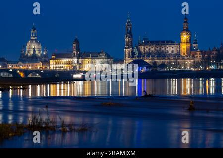 28. März 2020, Sachsen, Dresden: Blick in den Abend der historischen Altstadtszenerie an der Elbe mit der Kuppel der Frauenkirche (l-r), des Ständehauses, der Hofkirche, des Rathauses, des Hausmannsturms, des Residenzschlosses, der Kreuzkirche und der Semperoper. Wegen der aktuellen Krisensituation nimmt Dresden an diesem Samstag erstmals seit drei Jahren nicht mehr an der weltweit größten Umwelt- und Klimaschutzkampagne "Erdstunde" Teil. Hinter der "Earth Hour" steht die Umweltorganisation WWF und die Idee, dass Millionen von Menschen auf der ganzen Welt die Lichter für einen ausschalten Stockfoto