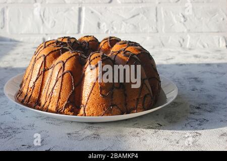 Ein selbstgebackener Kuchen wird von der Sonne angezündet. Am frühen Morgen. Frühstück. Hausgemachtes Backen mit Schokolade Stockfoto