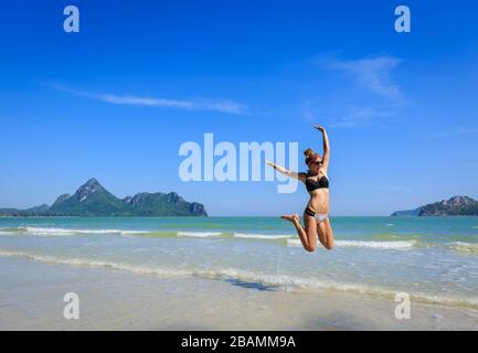 Junge Frau am Strand springen Stockfoto
