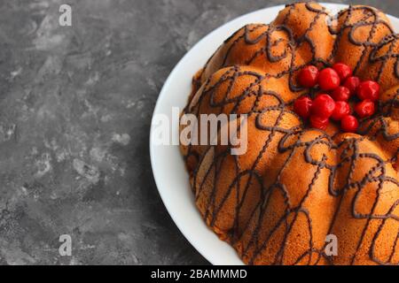 Hausgemachter Kuchen mit Beeren und Schokoladenvereisung. Sehr süßer Kuchen. Dessertkonzept. Dunkler und heller Hintergrund Stockfoto
