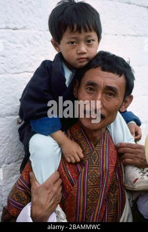 Ein Vater trägt seinen Sohn auf seinen Schultern bei Bhutans jährlichem Thimphy Tsechu Festival. (12-10-89) BX61 Stockfoto