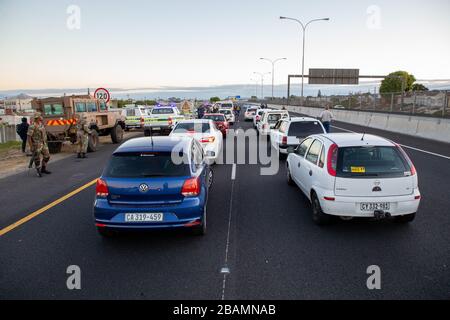 KAPSTADT, SÜDAFRIKA - Samstag, 28. März 2020: Mitglieder des South African Police Service und der South African National Defence Force stationieren an einer Straßensperre auf der vielbefahrenen Autobahn R300, nachdem die südafrikanische Regierung eine 21-tägige COVID-19-Sperre als Teil der Erklärung des Staates der nationalen Katastrophe durch Präsident Cyril Ramaphosa ausgerufen hatte. Das Gesundheitsministerium hat die Bewohner aufgefordert, die Vorschriften zu beachten, Hygiene zu üben, zu Hause zu bleiben und soziale Distanzierungen zu praktizieren. Foto von Roger Sedres Stockfoto