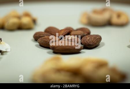 Verschiedene Arten von Nüssen in weißen Mandeln, Pistachios, Cashews, Erdnuss, Haselnuss, Trockenfrüchte Stockfoto