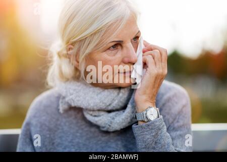 Seniorin mit einem Gewebe im Freien Stockfoto