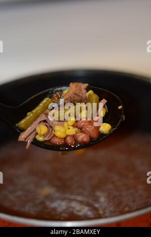 Großer Löffel, der herzhaftes hausgemachtes Rindfleisch und Gemüsesuppe aus einem Topf zubereitet. Nahaufnahme. Bunt. Stockfoto