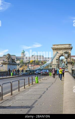 Budapest, Ungarn - 6. November 2019: Berühmte Szechenyi-Kettenbrücke, Hängebrücke, über die Donau in der ungarischen Hauptstadt. Touristen Sehenswürdigkeiten, Autos auf der Straße. Buda-Burg im Hintergrund. Stockfoto