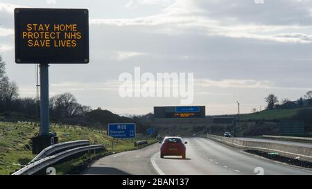 Glasgow, Großbritannien. März 2020. Abgebildet: Straßenschilder auf den Autobahnen M8 und M80, die lauten: "BLEIBEN SIE ZU HAUSE SCHÜTZEN Sie NHS RETTEN SIE LEBEN" die Pandemie von Coronavirus hat die britische Regierung gezwungen, eine Abschaltung aller britischen Großstädte anzuordnen und die Menschen zu Hause zu lassen. Das hat die Autobahnen und alle anderen Straßen frei von der üblichen Nase gelassen, um den Verkehr, der sonst da wäre, zu vereitelen. Kredit: Colin Fisher/Alamy Live News Stockfoto
