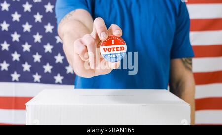Wahlhand mit "Ich habe heute gewählt"-Taste an der Box auf amerikanischer Flagge. Stockfoto