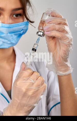 Frau Doktor Füllung Spritze mit Arznei aus Fläschchenröhrchen. Stockfoto