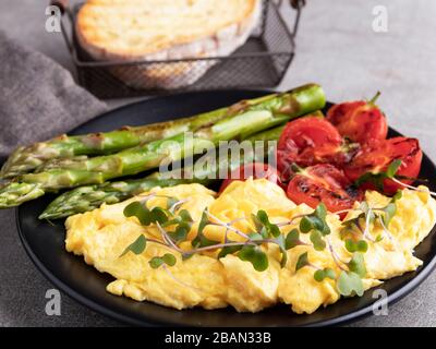 Rührei mit gebratenem Tomatenspargelfrühstück, gesundes Essen Stockfoto