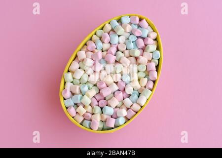 Farbige Mini-Marshmallows in Form eines ostereiers auf pinkfarbenem Hintergrund, Draufsicht Stockfoto