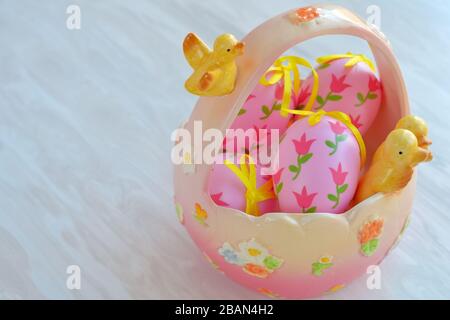 Osterkeramikkorb mit dekorativen, rosafarbenen Eiern, festlichem Hausdekor Stockfoto