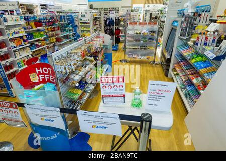 Coronavirus Warnschilder und Händewaschanlagen am Eingang einer Amcal Apotheke am internationalen Abflugterminal des Flughafens Sydney (Kingsford Smith) in Australien. Der Chemiker hatte die Barriere und Warnungen am Ladeneingang platziert, um Flugpassagiere, die gerade nach Australien gekommen waren, zu bitten, sich an "soziale Distanzierungsregeln" zu halten, um das Risiko einer Verbreitung des Coronavirus zu verringern. Stockfoto