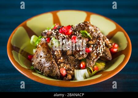 Pfanne mit traditionellem japanischem Yakitori-Gericht - gebratene Schachtelherzen mit Sesam, Teriyaki-Sauce und frischem Gemüse auf Holzbrett isoliert bei Stockfoto