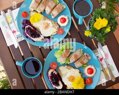 Wunderschönes farbenfrohes Frühlingsfrühstück mit einer Vielzahl von Speisen auf einem Holztisch mit Blumen. Stockfoto