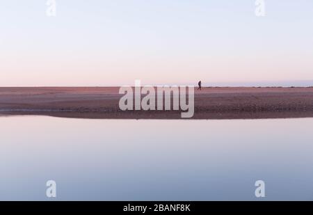 Frau, die am Strand von Aberdeen spazieren ging, spiegelte sich im Fluss Don, Schottland, wider Stockfoto